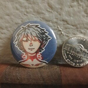May include: A round button with a blue background and a white character with silver hair. The character has red and white accents around their neck.