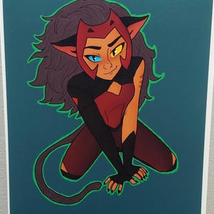 Op de afbeelding: Illustratie van een personage in een rode en zwarte outfit, met kattenoren en een staart. Het personage heeft één blauw en één geel oog, tegen een teal achtergrond met een groene rand.