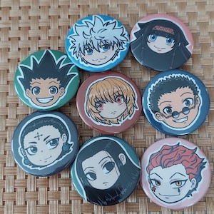 May include: Set of 8 round button pins featuring different characters from the anime Hunter x Hunter. The characters are Killua, Gon, Kurapika, Leorio, Hisoka, Chrollo, Illumi, and Uvogin. The pins are colorful and have a glossy finish.