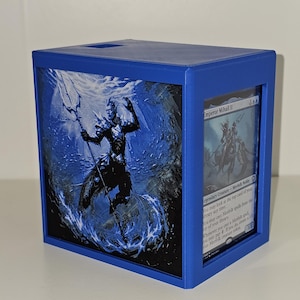 May include: A blue card storage box with a blue and black graphic of a warrior with a trident in water. The box has a card with the text "Emperor Mihail II" visible. The box is made of plastic.