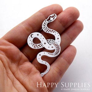 May include: White metal cutout of a snake with a crescent moon and stars on its body. The snake is curled up in a coil shape.