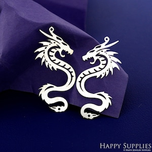 以下が含まれることがあります： 複雑なディテールが施された、銀色の金属製のドラゴンチャーム2個。ドラゴンは反対方向を向いており、上部にジュエリーに取り付けるための穴があります。