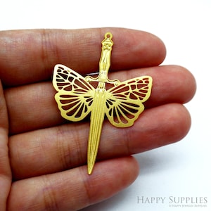 May include: Gold-toned metal charm featuring a sword with butterfly wings. The sword has a detailed design and the wings are cut out to create a delicate look.