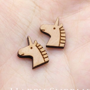 Two Horse Charms, made of natural wood, are on the hand of Jewelry Maker, waiting for DIY Earrings Studs.