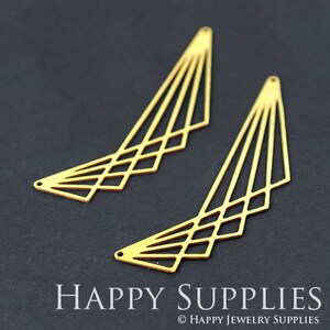 Puede incluir: Dos componentes de pendientes dorados de forma geométrica. Cada componente tiene un diseño en forma de abanico con una serie de líneas paralelas y recortes en forma de diamante. Los componentes están sobre un fondo oscuro. El texto "HAPPY SUPPLIES" está en la parte inferior.