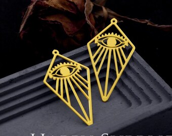 May include: Two gold-toned metal charms in a diamond shape, each featuring a central eye motif with radiating sunburst lines. Each charm has a small loop at the top for attachment. The text HAPPY SUPPLIES and © HAPPY JEWELRY SUPPLIES is visible.