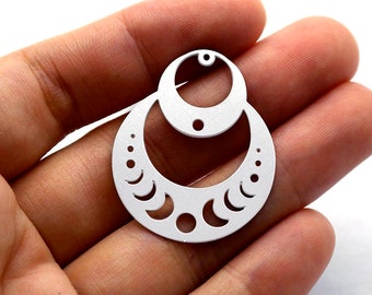 May include: Silver-toned metal earring with a double circle design. The outer circle has a crescent moon pattern and the inner circle is solid. The earring has a hole at the top for attaching a hook.