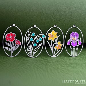 Pode incluir: Quatro pingentes ovais em tom prateado com designs florais em esmalte colorido. Os berloques retratam uma papoula vermelha, lírios-do-vale turquesa, um narciso amarelo e uma íris roxa. Cada pingente tem uma pequena argola no topo.