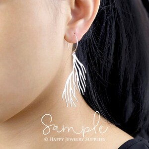 Peut inclure: Boucles d'oreilles pendantes en argent avec un design d&eacute;licat en forme de branche. Les boucles d'oreilles sont pr&eacute;sent&eacute;es sur l'oreille d'un mannequin.