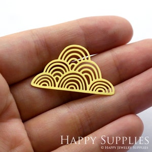 Könnte beinhalten: Ein goldfarbenes Schmuckelement aus Metall in flacher, wolkenartiger Form mit einem sich wiederholenden Muster aus konzentrischen Halbkreisen. Das ausgeschnittene Design erzeugt eine Reihe ineinandergreifender Bögen für ein filigranes Aussehen.