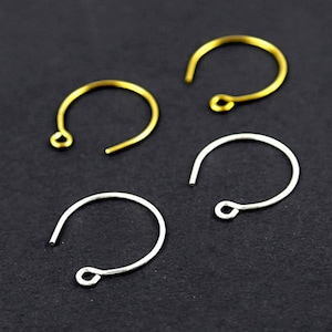 May include: Two gold-toned and two silver-toned metal earring hooks. Each hook features a circular wire design with a small loop at one end for attaching jewelry components. The hooks are arranged in a square formation on a dark surface.