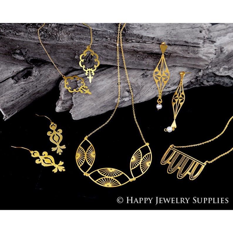 Pu&ograve; includere: Un set di gioielli dorati con collane e orecchini con intricati disegni geometrici. I gioielli sono esposti su un pezzo di legno invecchiato. &copy; HAPPY JEWELRY SUPPLIES