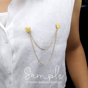 Peut inclure: Un collier &agrave; double cha&icirc;ne dor&eacute;e avec un pendentif en forme d'&eacute;cureuil et de gland. Le collier est port&eacute; sur une chemise blanche.