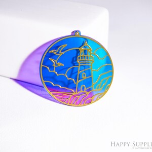 以下が含まれることがあります： 灯台のシーンが描かれた、丸い青と金のペンダント。灯台、雲、カモメのデザイン。ペンダントは金の輪郭と青色のイリデセントな背景が特徴です。ジュエリーアイテムです。