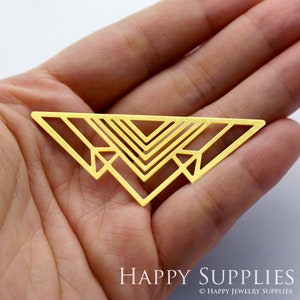 May include: A gold-colored metal jewelry component featuring a wide, flat triangular frame with an intricate openwork design of nested V-shapes and geometric arrow-like motifs. The piece has a smooth, matte finish and a symmetrical structure.