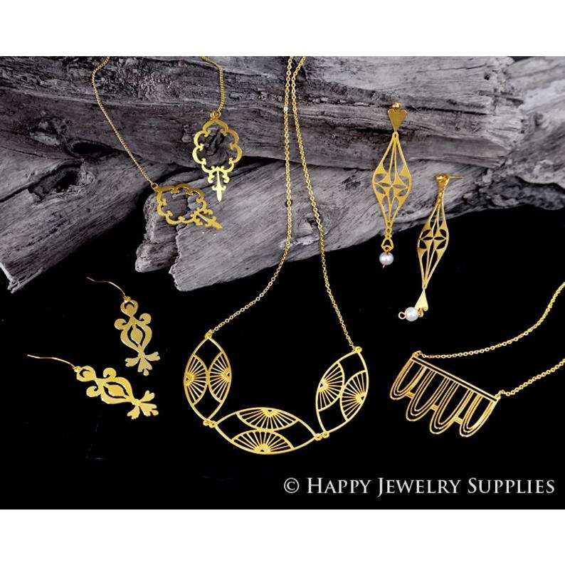 May include: A set of gold-toned jewelry featuring intricate geometric designs. The set includes a necklace, earrings, and a pendant. The jewelry is displayed on a wooden surface.