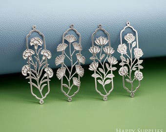 Puede incluir: Cuatro colgantes florales plateados con diferentes diseños de flores. Cada colgante presenta un arreglo floral único, incluyendo claveles, hojas de ginkgo, flores de loto y rosas, dentro de un marco decorativo. Ideal para la creación de joyas.