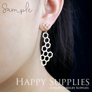 Peut inclure: Boucles d'oreilles g&eacute;om&eacute;triques en forme de nid d'abeille dor&eacute;es avec un petit charme en forme de diamant en haut. Les boucles d'oreilles sont pendantes et ont un design d&eacute;licat et moderne.