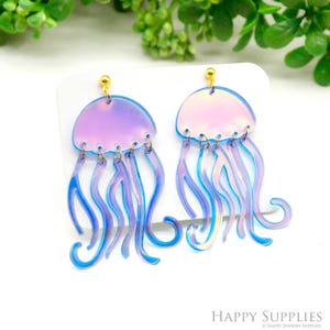 May include: A pair of iridescent blue and purple jellyfish dangle earrings with gold hooks. The jellyfish are made of clear acrylic with a holographic finish.