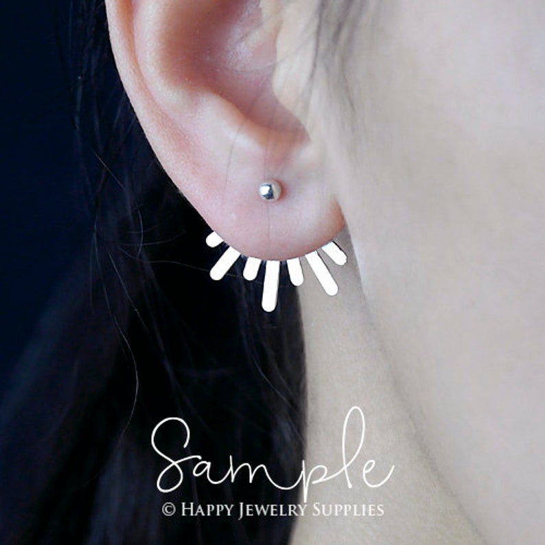 Peut inclure: Boucle d'oreille argent&eacute;e avec un motif de soleil. La boucle d'oreille est en m&eacute;tal fin et a un look d&eacute;licat et f&eacute;minin.