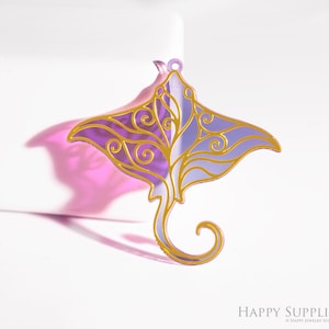 May include: A purple and gold-coloured stingray-shaped pendant. The pendant features a decorative gold filigree design outlining the edges and interior details. The stingray has a curved tail and a small hole at the top for hanging.
