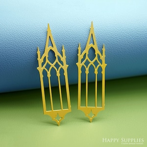 May include: Two gold-colored, gothic-style window-shaped metal cutouts. Each cutout features an arched top, vertical lines, and decorative geometric shapes. The cutouts are displayed on a blue and green background.