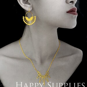 Pu&ograve; includere: Una collana d'oro con un ciondolo geometrico e un paio di orecchini abbinati in oro con un design a forma di ventaglio. I gioielli sono esposti su un manichino con uno sfondo nero. Il testo "HAPPY SUPPLIES" &egrave; visualizzato nella parte inferiore dell'immagine.