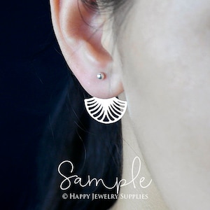 May include: A pair of silver earrings with a delicate fan-shaped design. The earrings are shown on a model's ear.