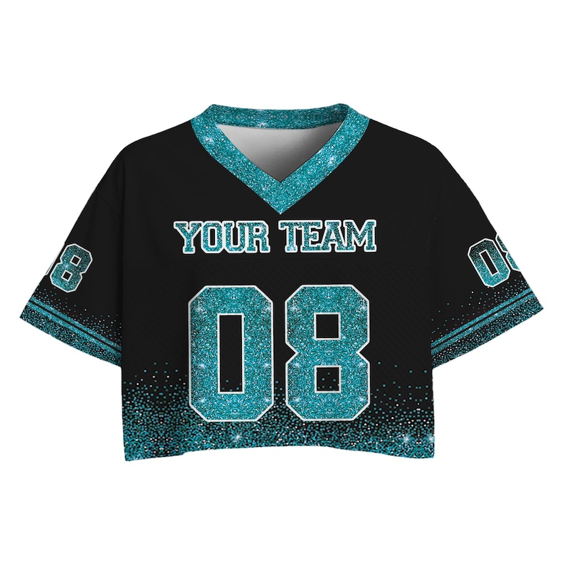 Puede incluir: Camiseta corta negra con detalles de purpurina turquesa. Presenta el texto "YOUR TEAM" y el n&uacute;mero "08" en purpurina turquesa. La camiseta tiene cuello en V y mangas cortas, con ribete de purpurina turquesa.