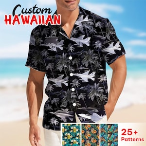 May include: Black Hawaiian shirt with a pattern of fighter jets and palm trees. The shirt has a button-down front and short sleeves. The words "Custom Hawaiian" are printed in red and white at the top left. Additional patterns are shown at the bottom.