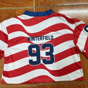 May include: A short-sleeved, cropped athletic jersey featuring a red and white wavy striped pattern. The back displays the name WINTERFIELD in dark blue lettering above the large dark blue number 93, with the number 93 also printed on each sleeve.