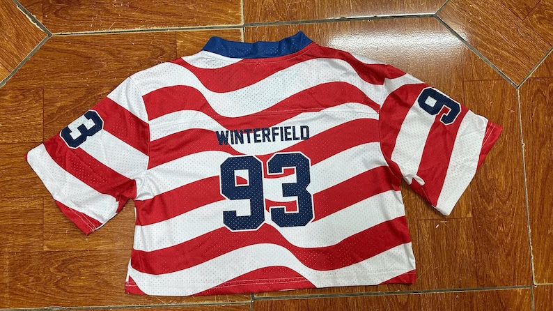 May include: A short-sleeved, cropped athletic jersey featuring a red and white wavy striped pattern. The back displays the name WINTERFIELD in dark blue lettering above the large dark blue number 93, with the number 93 also printed on each sleeve.