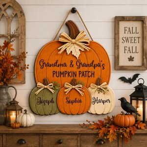 Puede incluir: Un adorno de pared de madera con forma de calabaza naranja grande, tallo marrón y lazo de rafia. Incluye el texto Grandma & Grandpa's PUMPKIN PATCH sobre tres calabazas más pequeñas en verde, naranja y blanco, cada una con un nombre.