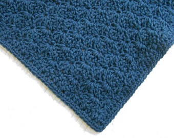 May include: A close-up of a blue crocheted blanket with a textured pattern.