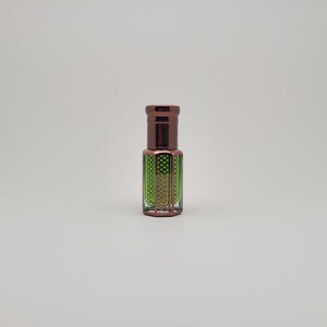 Close-up view of Mosswood Oud natural fragrance oil bottle with a white backdrop, showing the rich amber hue of the oud oil inside