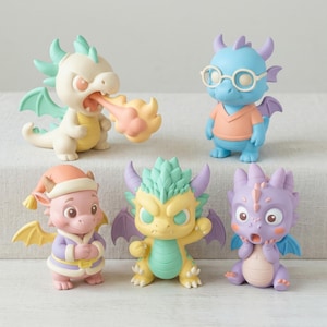 Puede incluir: Colección de cinco figuras de dragones coloridos. Cada dragón tiene características únicas, incluyendo diferentes colores, expresiones y accesorios. Un dragón escupe fuego, mientras que otro lleva gafas. Las figuras se exhiben sobre una superficie neutra.