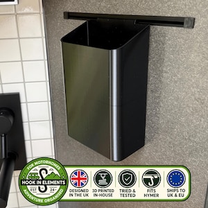 May include: A black rectangular storage container with an open top, designed to hang from a horizontal black rail. The container features a smooth, matte finish and a deep, hollow interior, providing a functional solution for organising small items.