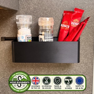 Peut inclure: Un bac de rangement rectangulaire noir fixé au mur, contenant deux moulins à épices transparents et trois sachets de café rouges Kenco. Sous le bac se trouve un logo vert et blanc avec le texte Hook In Elements, Designed in the UK, 3D Printed In-House, Tried & Tested, Fits Hymer, et Ships to UK & EU.