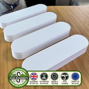 Könnte beinhalten: Vier weiße, längliche, oval geformte Kunststoffkomponenten mit einer strukturierten Oberfläche. Ein Logo unten enthält den Text: FOR MOTORHOMES HOOK IN ELEMENTS EST 24 ADVENTURE ORGANISED, DESIGNED IN THE UK, 3D PRINTED IN-HOUSE, TRIED & TESTED, FITS HYMER, SHIPS TO UK & EU.