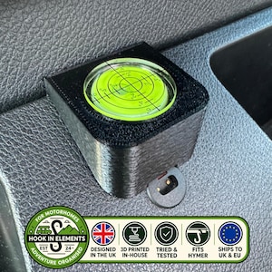 May include: A black 3D-printed square housing containing a circular lime green bullseye spirit level with black crosshair markings and degree indicators. The device features a small circular mounting tab at the base for secure installation.
