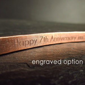 Inside of a bronze cuff bangle showing engraving that says "Happy 7th Anniversary xxx"