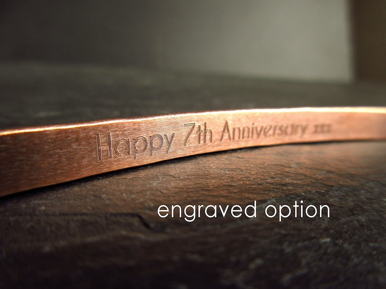 Inside of a bronze cuff bangle showing engraving that says "Happy 7th Anniversary xxx"