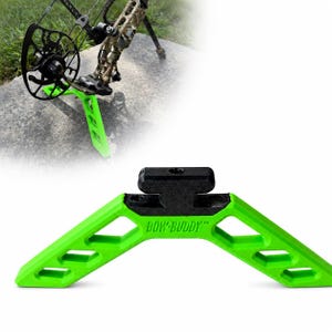 May include: A bright green bow stand with a black top mounting piece, featuring the text BOW-BUDDY embossed on the center. The stand has a wide, angled base with triangular cutouts on each side, designed to support a compound bow upright.
