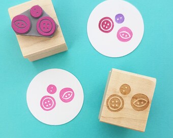 May include: Four wooden blocks with different designs of buttons and leaves. The blocks are on a turquoise background.