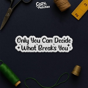 May include: Embroidered patch with the text "Only You Can Decide What Breaks You". The patch has a white border and is on a dark blue background. Sewing tools, including scissors and a tape measure, are arranged around the patch.