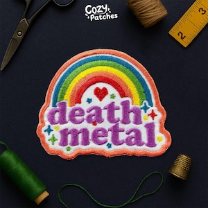 Peut inclure: Écusson brodé avec un arc-en-ciel et les mots "death metal" en violet. Le patch a une bordure blanche et comprend un cœur rouge et des étoiles. Le logo Cozy Patches est dans le coin supérieur gauche.