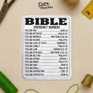 May include: A white embroidered patch with the text "BIBLE EMERGENCY NUMBERS" in black. The patch lists Bible verses for various feelings like sadness, worry, and fear. The patch is surrounded by sewing tools.