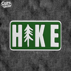 May include: Green and white embroidered patch with the word "HIKE" and a stylized pine tree in the center. The patch is rectangular and has a white border.
