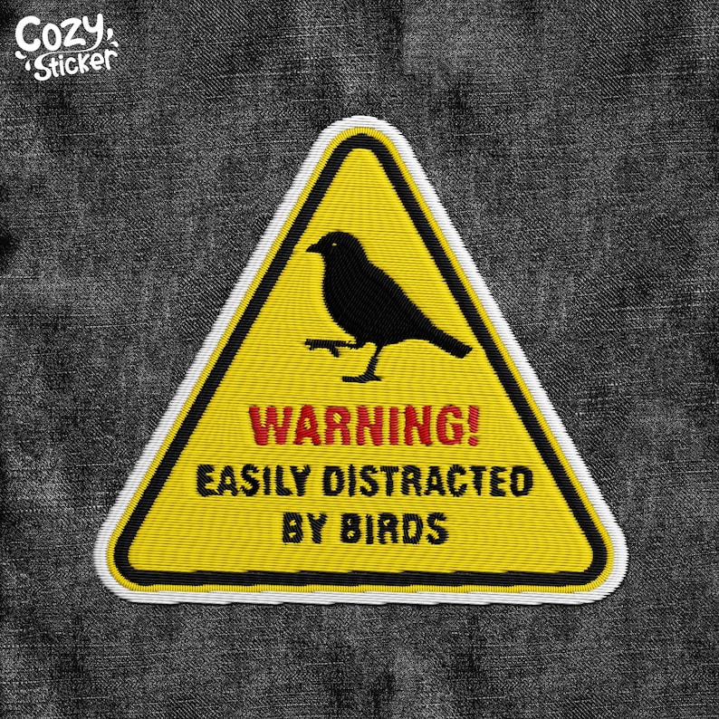 Pode incluir: Patch bordado com um sinal de aviso triangular amarelo com uma silhueta de p&aacute;ssaro preto. O texto "WARNING! EASILY DISTRACTED BY BIRDS" est&aacute; em vermelho e preto. O patch tem uma borda branca e o texto "Cozy Sticker".