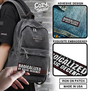 May include: A gray backpack with the text "RADICALIZED BY BASIC DECENCY" on a patch. The image also shows an adhesive patch and an embroidered patch with the same text. The patches are iron-on and made in the USA.